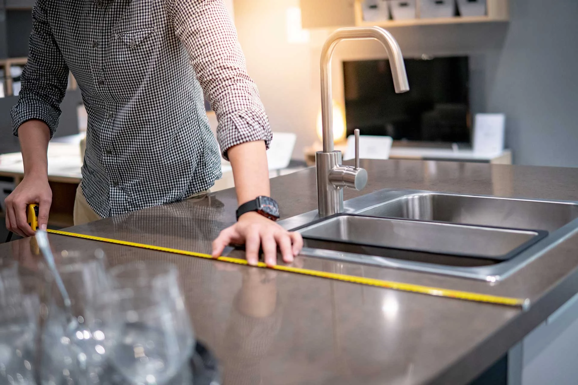 A person measuring a counter top with a measuring tape.