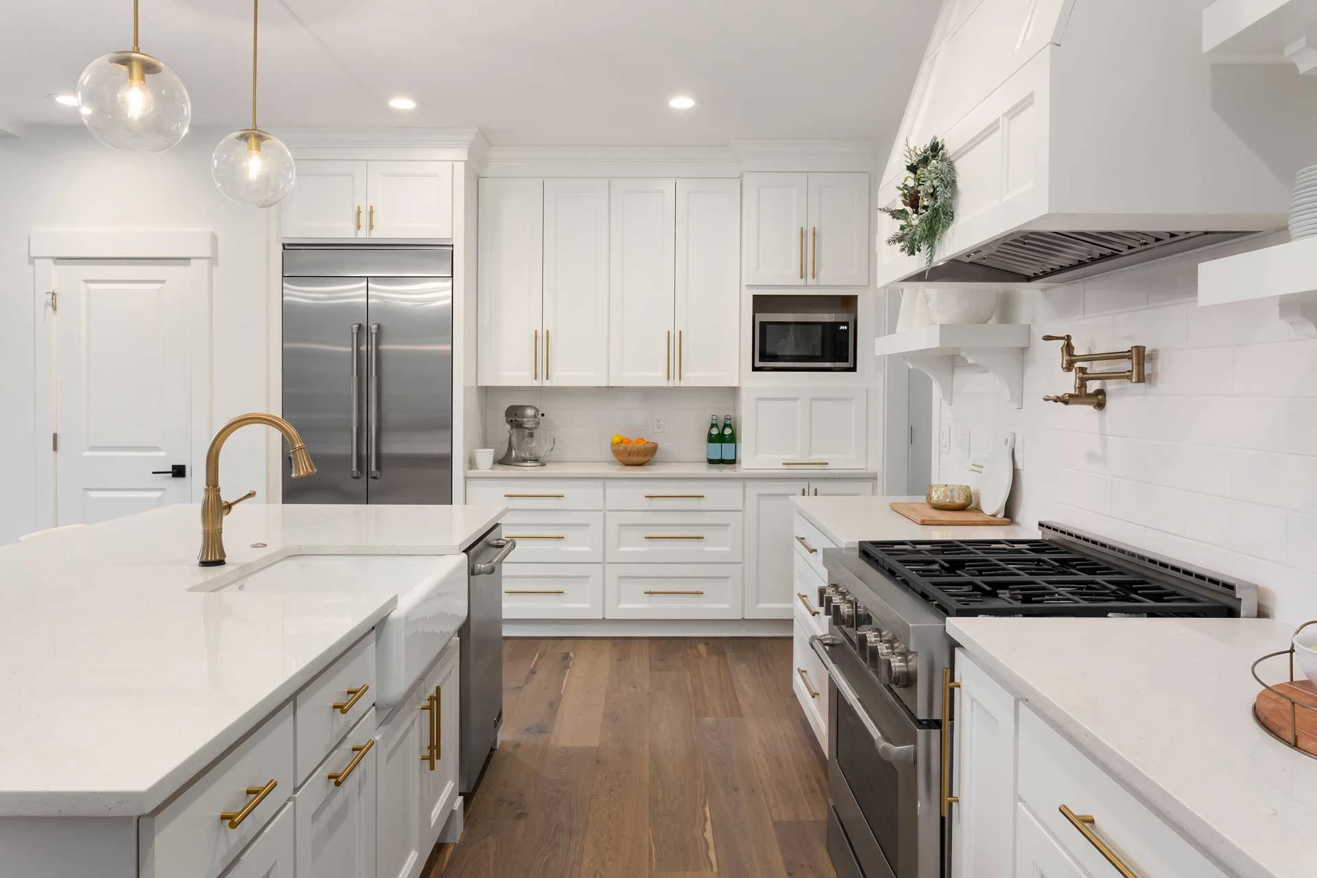 A kitchen with white cabinets and gold accents.