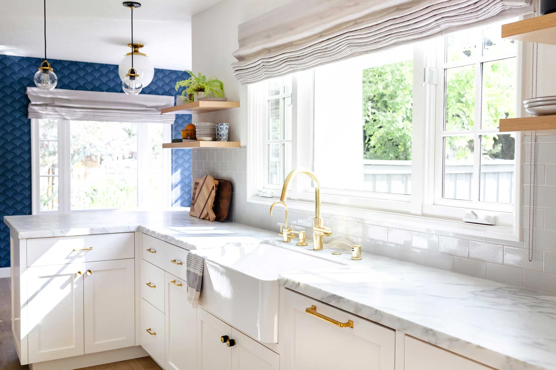 A kitchen with white cabinets and marble counter tops.