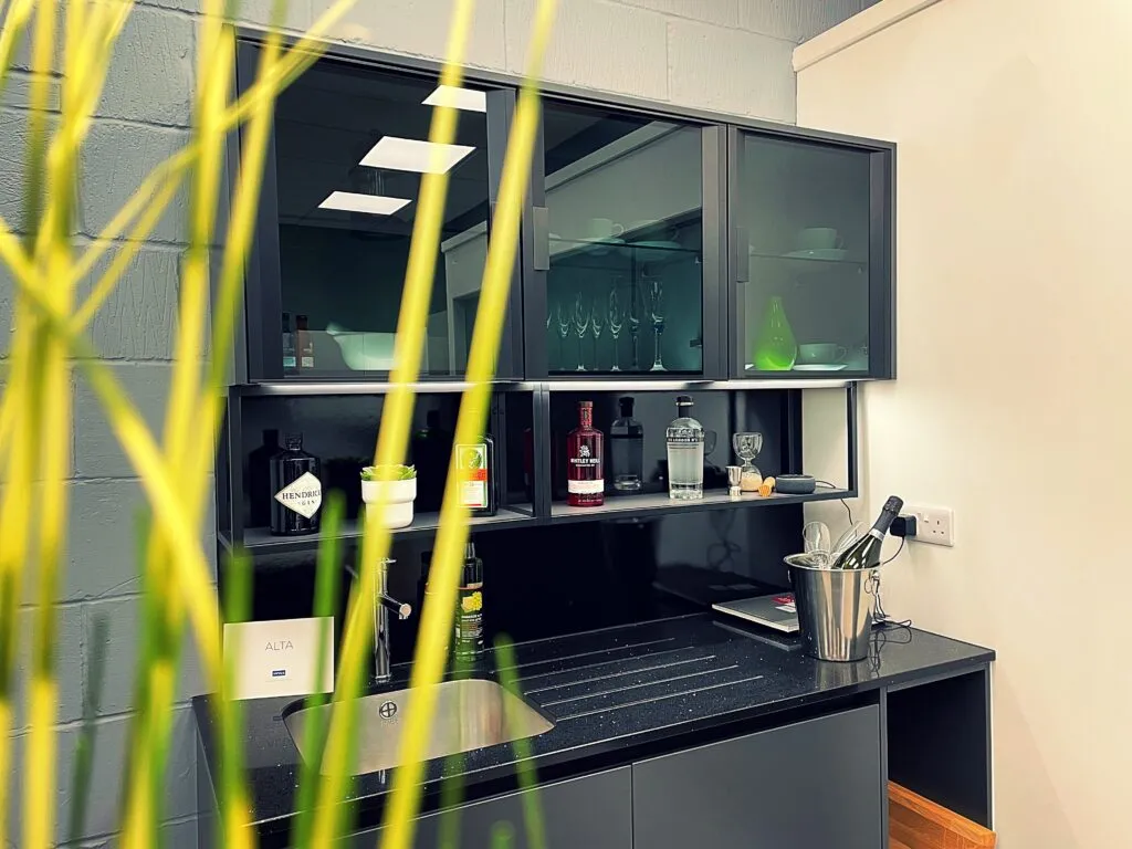 A kitchen with a black counter top next to a green plant.